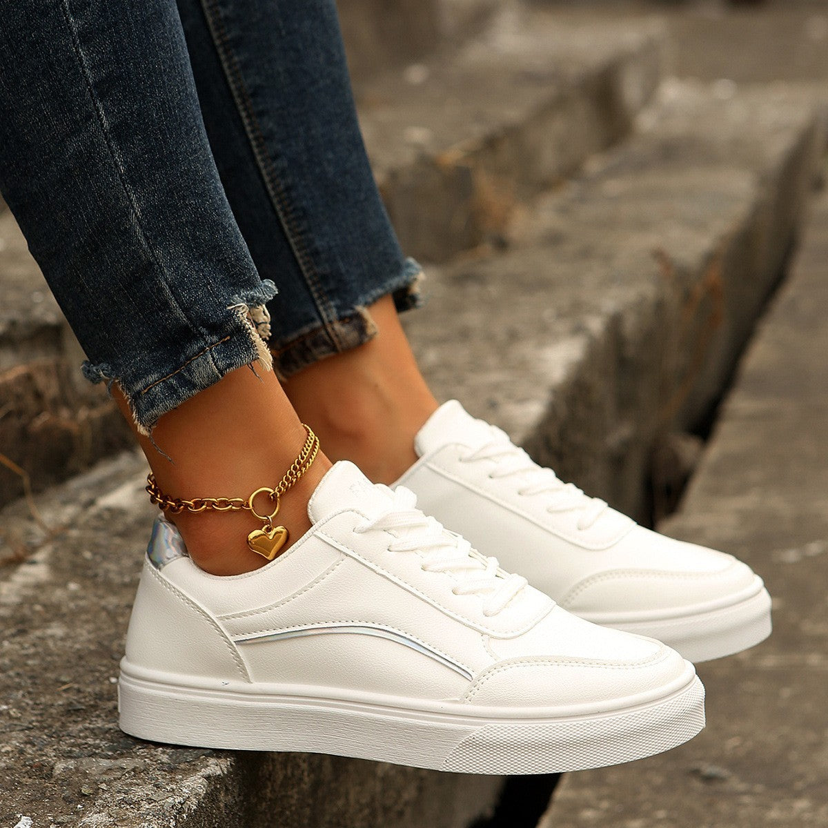 White sneakers worn with blue jeans on a stone step